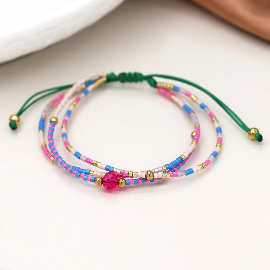 The Pink & Blue Mix Adjustable Beaded Bracelet is a sophisticated accessory, featuring pink, blue and gold beads on a green cord with a central pink bead for an added touch of luxury jewellery.