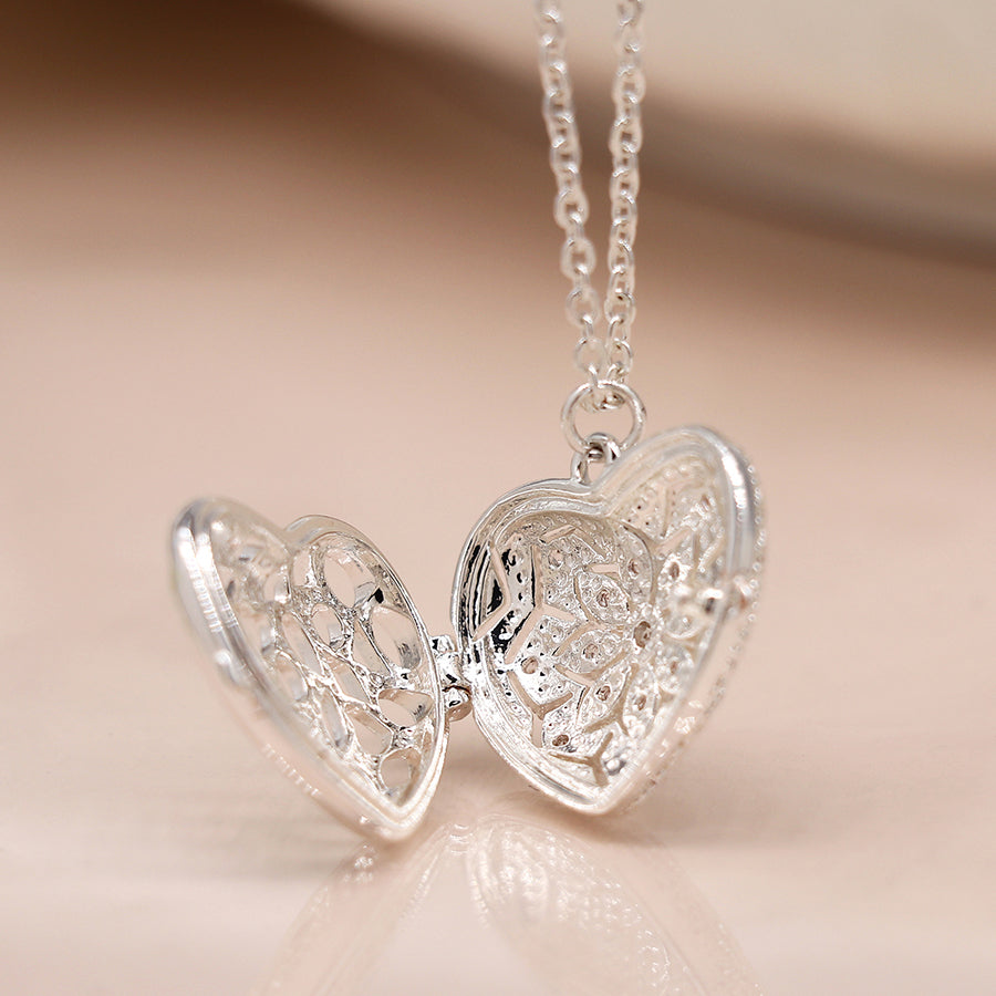 A stunning silver-plated heart-shaped locket with intricate floral patterns, this piece is a must-have in any jewellery collection. It’s elegantly attached to a delicate chain, perfect for keeping cherished memories close.