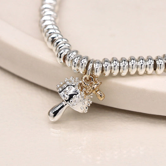 Silver-plated charm bracelet featuring a toadstool charm, elegantly displayed on a light-coloured surface.