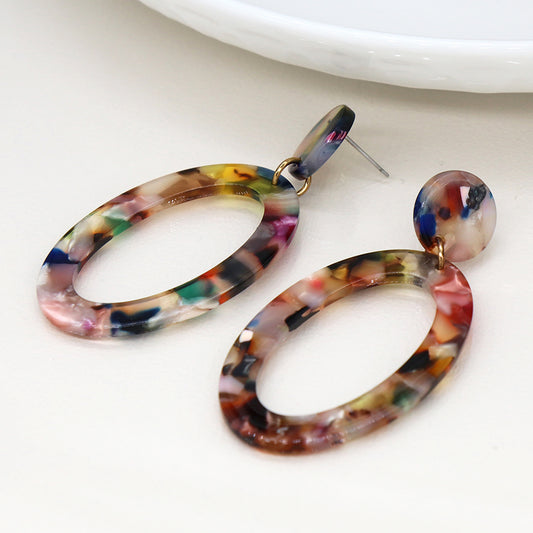 Unique multicoloured oval drop earrings showcase a marbled pattern on a white surface, exuding a captivating terrazzo effect.