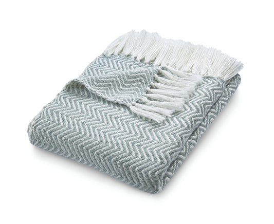 The eco-friendly folded grey and white Herringbone Throw, crafted from recycled plastic bottles, features a chevron pattern with fringed edges on top.