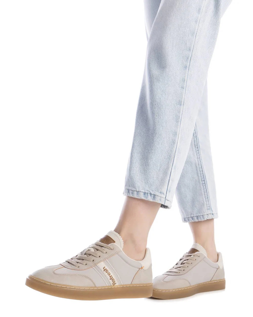 A person wearing light-wash jeans and beige trainers with brown soles, VAGABOND branding on the side, and a non-slip rubber sole for extra comfort.