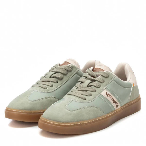 A pair of sage green low-top trainers with adjustable lace-up fastening, gum soles, and Porsche branding on the side.