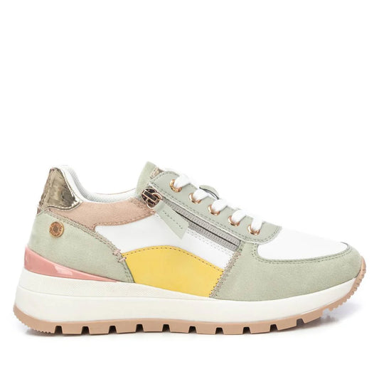A pastel-coloured vegan trainer with white, light green, yellow, beige, and metallic gold accents features laces, a side zip for a customisable fit, and a thick white non-slip rubber sole with tan tread.