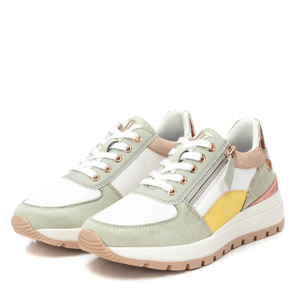 A pair of lace-up trainers with white, light green, beige, and yellow panels, featuring side zips, chunky beige soles, and a non-slip rubber sole for added stability.