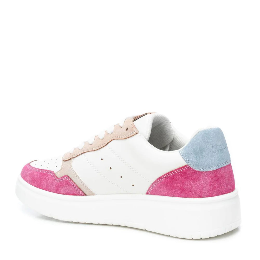 A white vegan trainer with pink suede accents, a blue heel, beige details, and a thick non-slip rubber sole is shown at an angle.