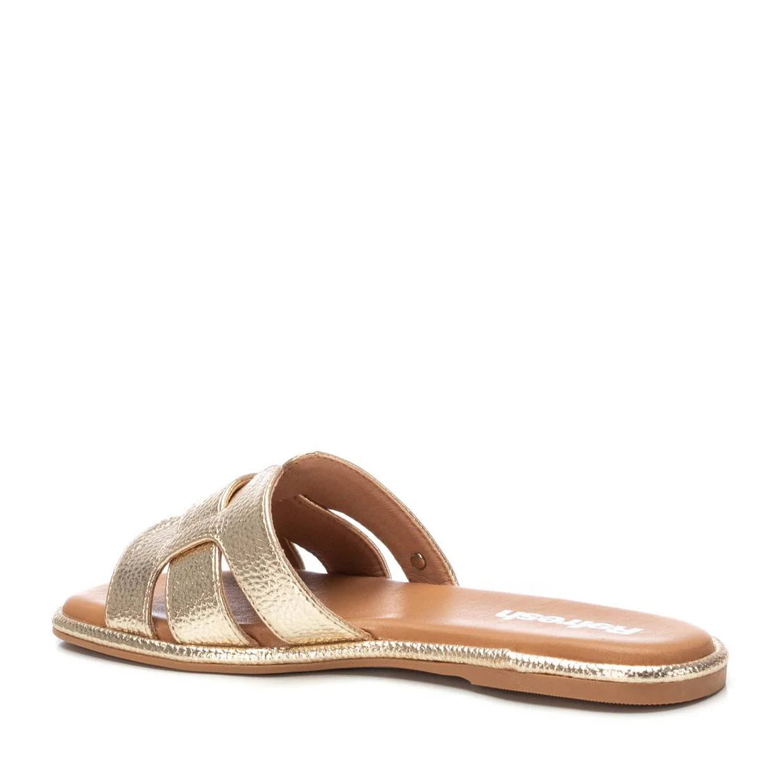 A gold women’s sandal with an open toe, cut-out straps, and a flat sole crafted from premium leather, shown from a rear side angle.