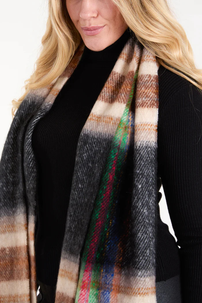 A person wearing a black ribbed polo neck jumper and a cosy winter accessory—a multicoloured tartan scarf—pictured from the shoulders to the waist.