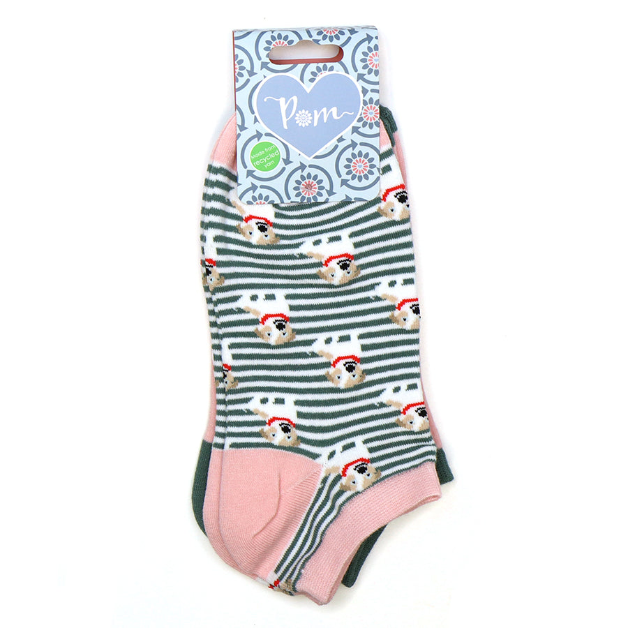 A pair of striped ankle socks with a pattern of dogs wearing Santa hats, featuring pink heels and toes, made from recycled materials and attached to Pom-branded packaging.