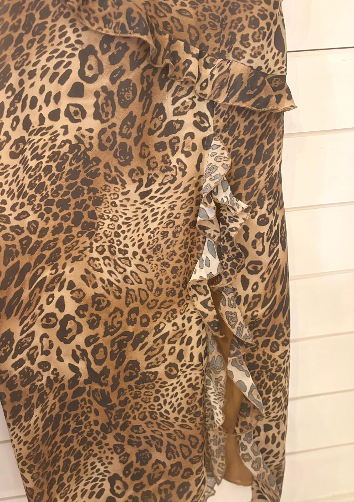 Brown and black leopard print fabric with a ruffled edge and side slit, this Leopard Long Dress in Size 12 is showcased against a light-coloured wooden background.