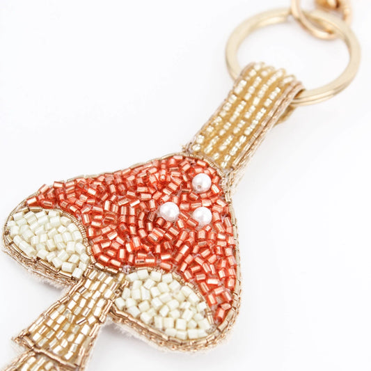Handcrafted in India, this mushroom keyring features a beaded design with red, white, gold, and copper beads for a unique touch.