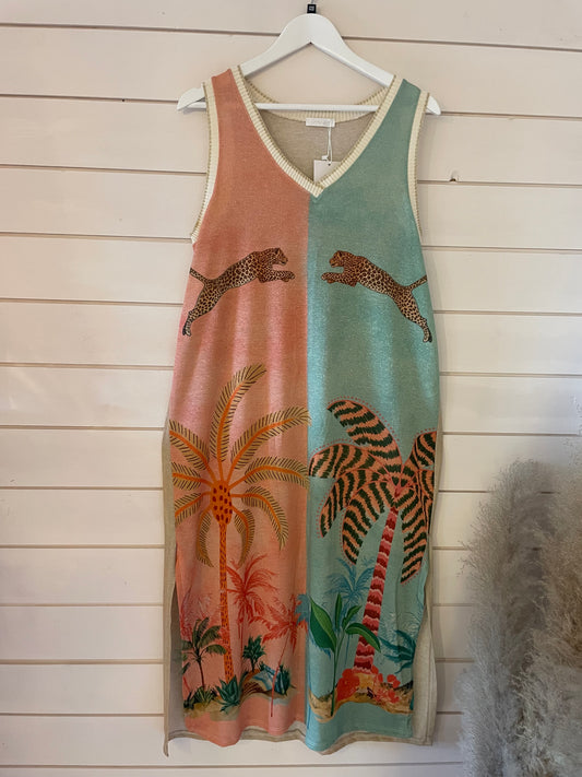 Sleeveless maxi dress on a white hanger, showcasing a split-colour design with leopards, palm trees and tropical plants against a shiplap wall backdrop, made from vegan materials.