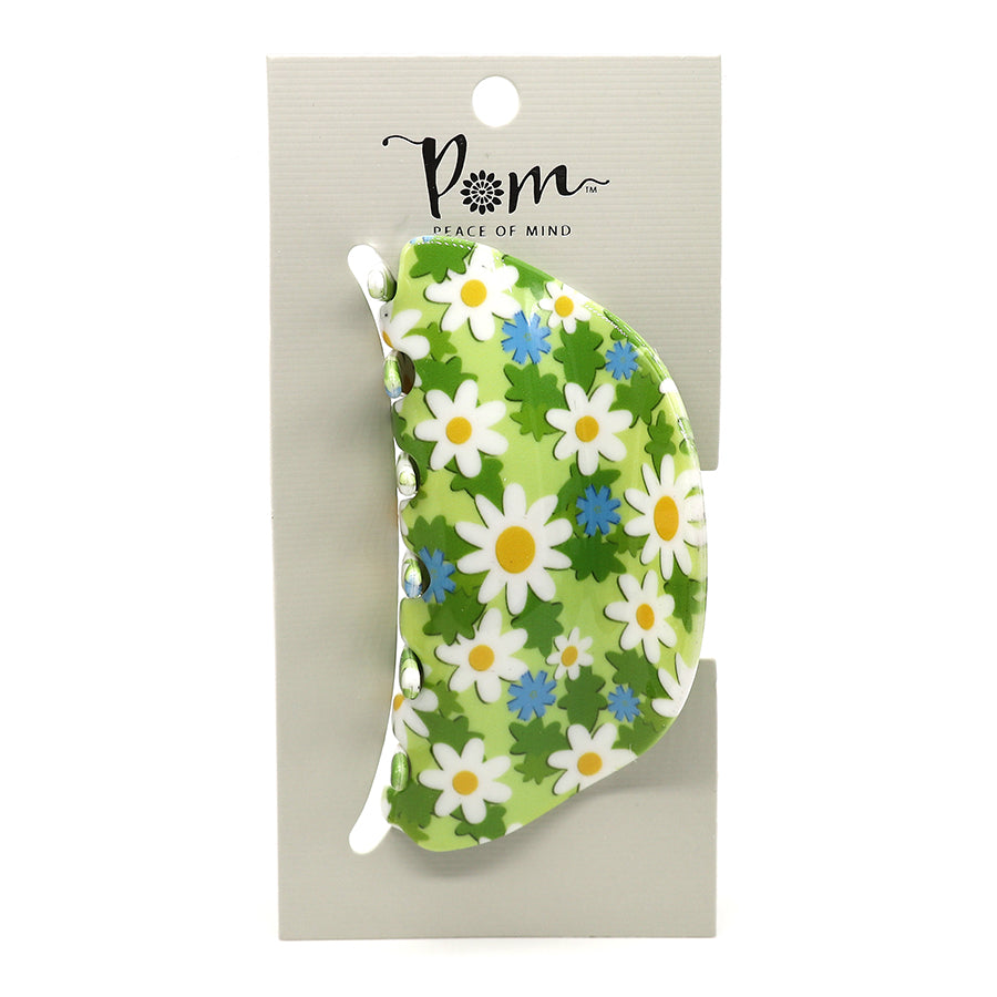 A green floral hair claw featuring white and blue flower designs is attached to a beige card labelled Pom Peace of Mind, crafted from durable acrylic for a luxurious accessory.