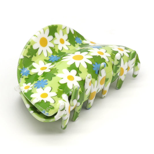 A floral claw clip featuring a green base, adorned with white daisies and blue flowers, crafted from durable acrylic for a luxurious accessory.