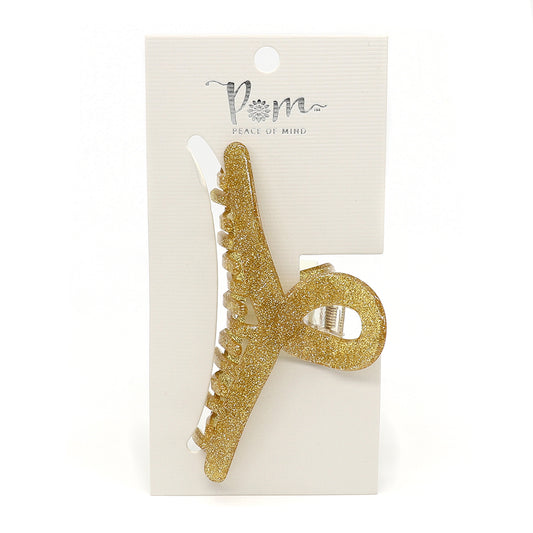 The POM Peace of Mind hair clip, beautifully set on delicate white packaging, features a unique looped design with luxurious acrylic in Champagne Glitter.