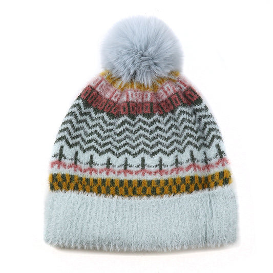 A cruelty-free knitted winter hat with a large grey pom-pom, featuring a vibrant multi-pattern design in black, gold, red, and pink on a light grey background.