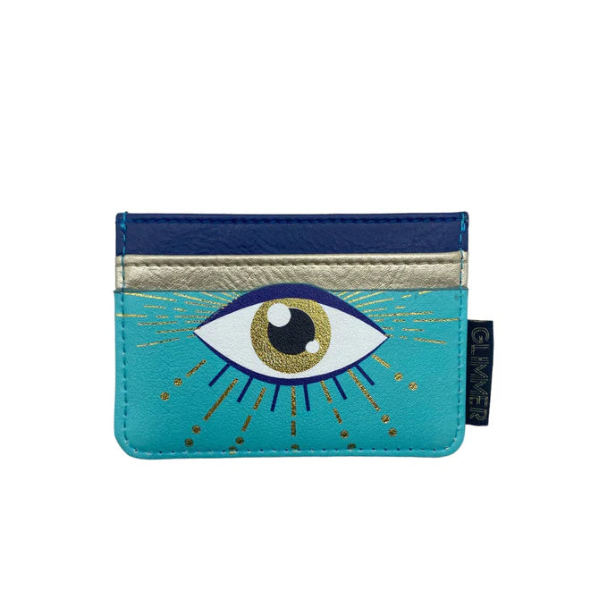 A turquoise card holder with metallic blue and gold sections, featuring an illustrated eye with gold rays on the front—made as a cruelty-free, vegan handbag accessory.