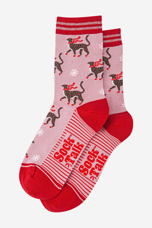 Cheerful pink and red socks featuring black cats in red scarves, white snowflakes, and ‘Sock Talk’ wording on the soles—delightfully playful socks to add charm to your winter wardrobe.