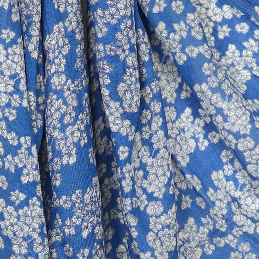 Close-up of blue fabric featuring a small white floral print pattern, perfect for crafting an elegant scarf.