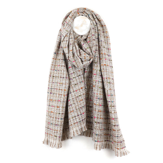 A soft blend scarf in beige with a multicoloured checked pattern and fringed edges, this cosy winter accessory hangs on a hook against a white background.