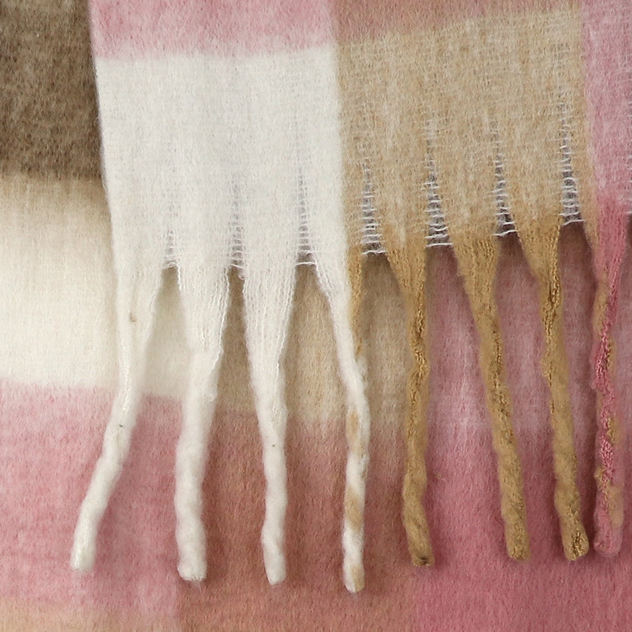 Close-up of a pale pink chunky checked scarf with twisted fringe, crafted from soft wool in blocks of white, beige, and pink.