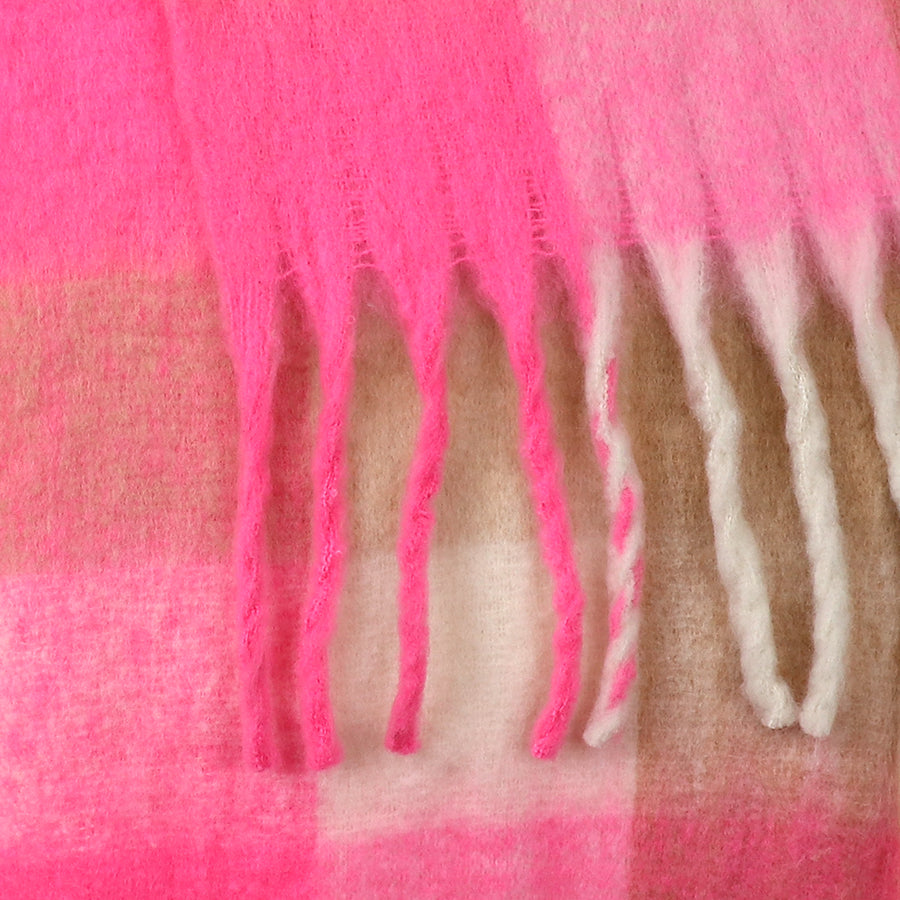 Close-up of a chunky chequered scarf in soft wool, showcasing pink, beige, and white blocks with fringed edges—a cosy accessory for chilly days.
