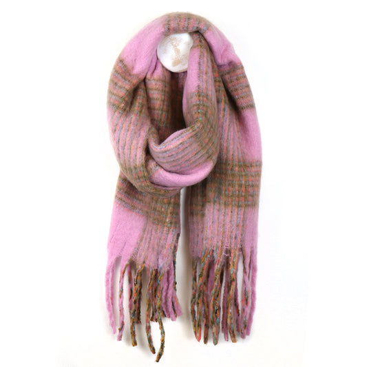 A chunky chequered scarf in pink and brown with fringed ends hangs on a white wall, making it an ideal accessory for chilly weather.
