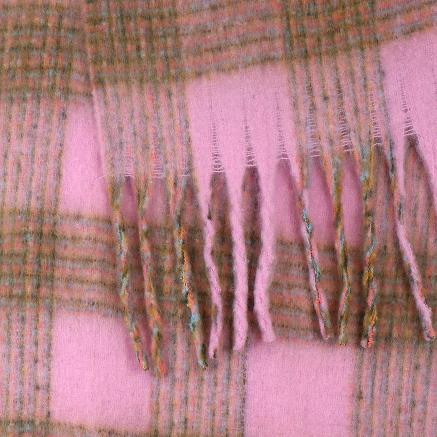 Close-up of a chunky chequered scarf in pink and green wool with fringed ends, highlighting its soft texture and woven pattern—a cosy accessory for cold weather.