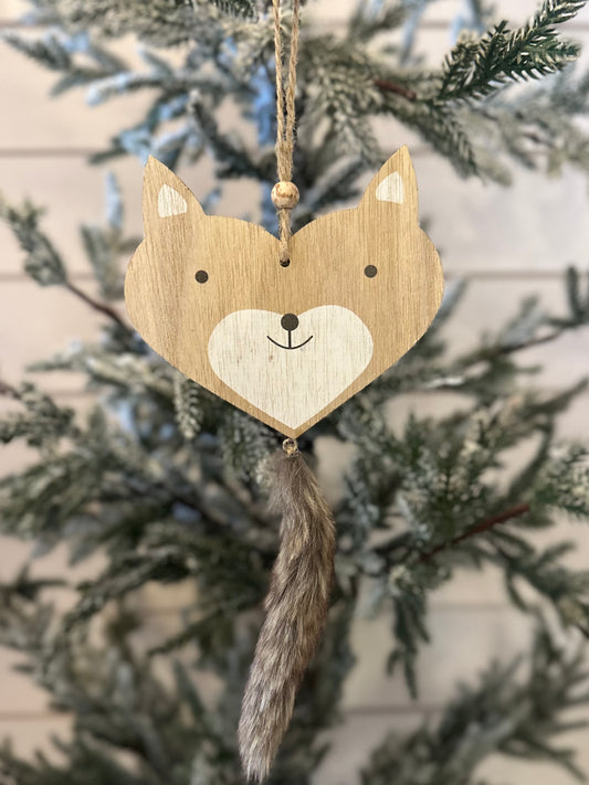 Wooden fox Christmas decoration with painted details and a faux fur tail, hanging from a branch of an artificial, snow-dusted Christmas tree—a delightful addition to your woodland Christmas décor.