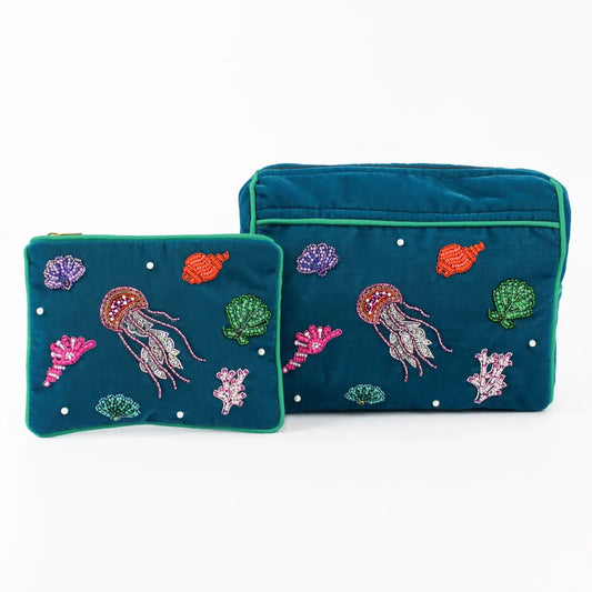 Two teal make-up bags featuring embroidered jellyfish designs and other marine elements, such as shells and corals, bring a colourful blue sea theme to life on a crisp white background.