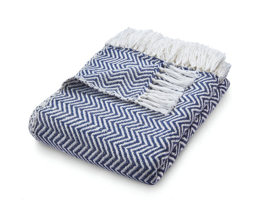 Folded blue and white chevron-patterned Herringbone Throw with fringed edges, crafted from recycled plastic bottles, lying on a white surface.