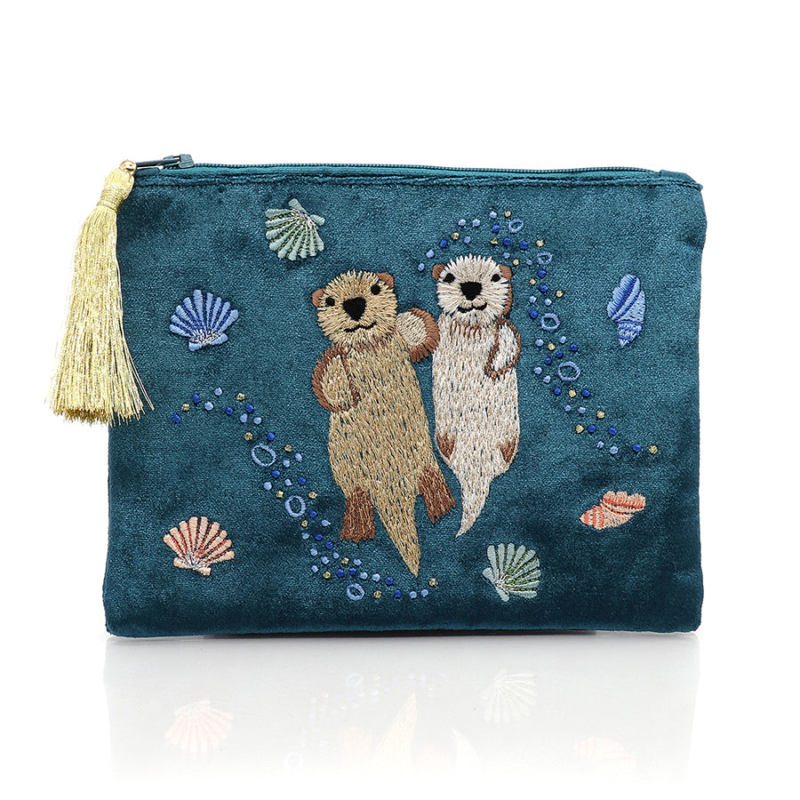 Dusky teal blue cotton velvet pouch featuring embroidered otters holding hands, surrounded by seashells and bubbles. Finished with a metallic gold tasselled zip for a touch of elegance.