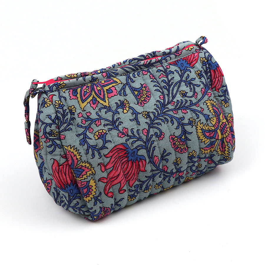 A quilted make-up bag with a zip fastening, showcasing a colourful floral and paisley design in blue, pink, and yellow on a light grey background.
