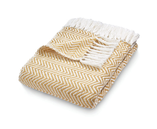 This eco-friendly Herringbone Throw features a yellow and white pattern with fringe, neatly folded. Crafted from recycled plastic bottles, it combines sustainability with style.