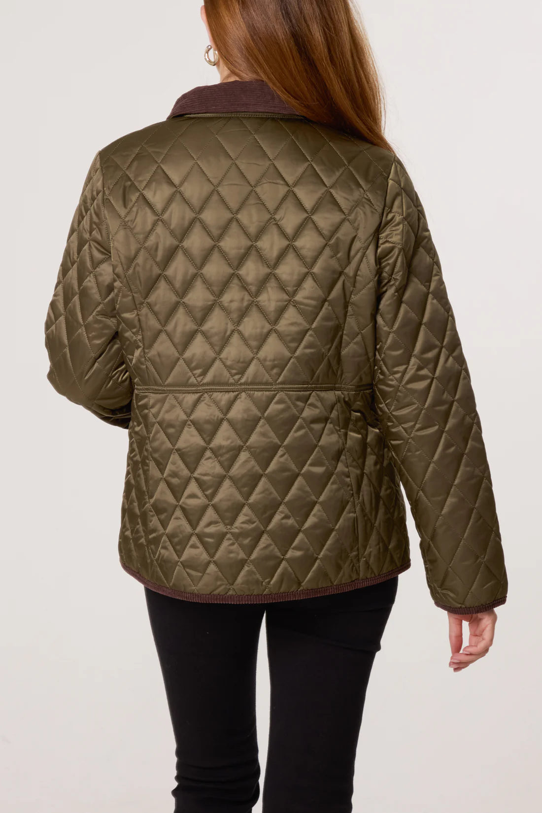 A person in a diamond-quilted olive green jacket and black trousers, seen from behind against a plain background, emphasising the coat’s thermal insulation.