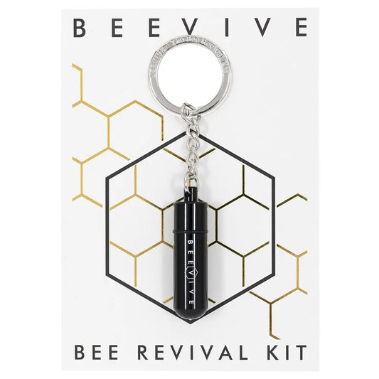 A small black keyring labelled BEEVIVE is attached to a card reading Bee Revival Kit, featuring a hexagonal honeycomb design that highlights environmental awareness and bee food syrup support.