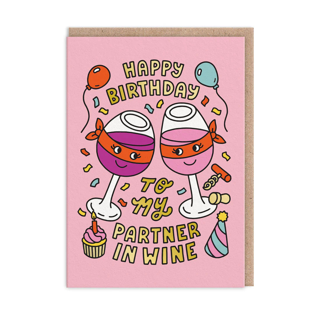 A pink birthday card showing two cartoon wine glasses with smiling faces, surrounded by balloons, confetti, a cupcake, and a party hat. The text says: Happy Birthday to my partner in wine.