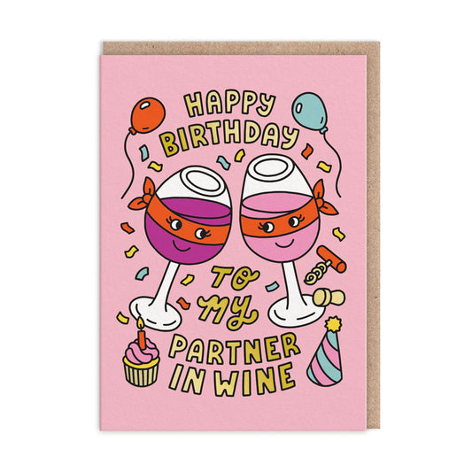 A pink birthday card showing two cartoon wine glasses with smiling faces, surrounded by balloons, confetti, a cupcake, and a party hat. The text says: Happy Birthday to my partner in wine.