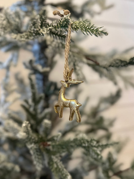 A gold hanging reindeer ornament dangles from a twine string on a frosted artificial pine branch, adding a festive touch to your Christmas decor.