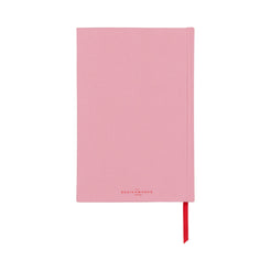A closed, pink, vintage book-inspired notebook with a red ribbon bookmark visible at the bottom.