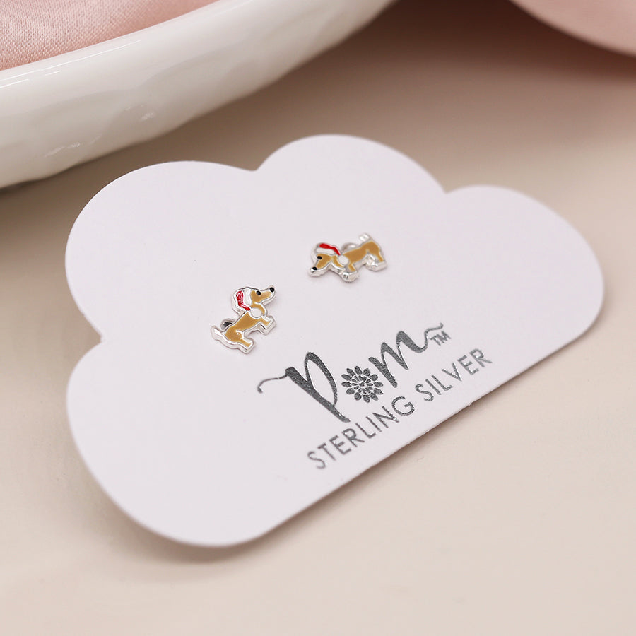 A pair of sterling silver dachshund dog stud earrings with red and white hats, presented on a cloud-shaped card labelled PM Sterling Silver—perfect holiday jewellery or adorable silver Christmas earrings.
