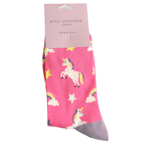 Unicorns Hot Pink Socks: Pink bamboo and cotton socks featuring unicorn, rainbow, and star patterns, packaged with a Miss Sparrow London label. These vegan-friendly socks also have a grey toe area.