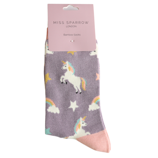 A pair of Miss Sparrow London vegan-friendly lavender unicorn-themed socks, featuring pastel stars and rainbows on a light purple background, crafted from a soft bamboo-rich blend.