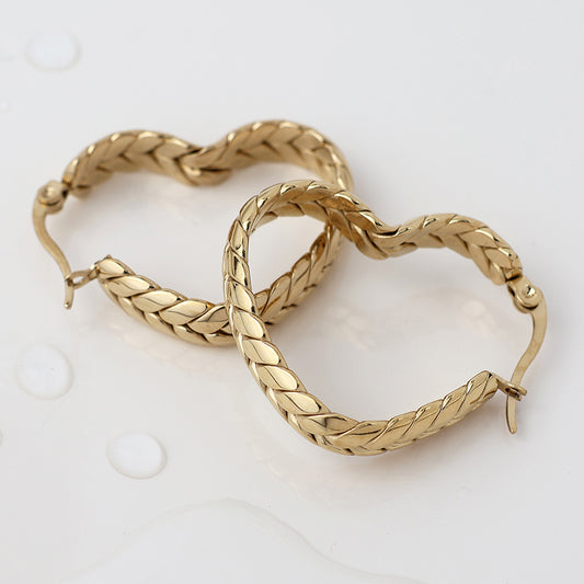 A pair of waterproof, gold-plated hoop earrings with a braided design, shown on a white surface with small droplets of water.