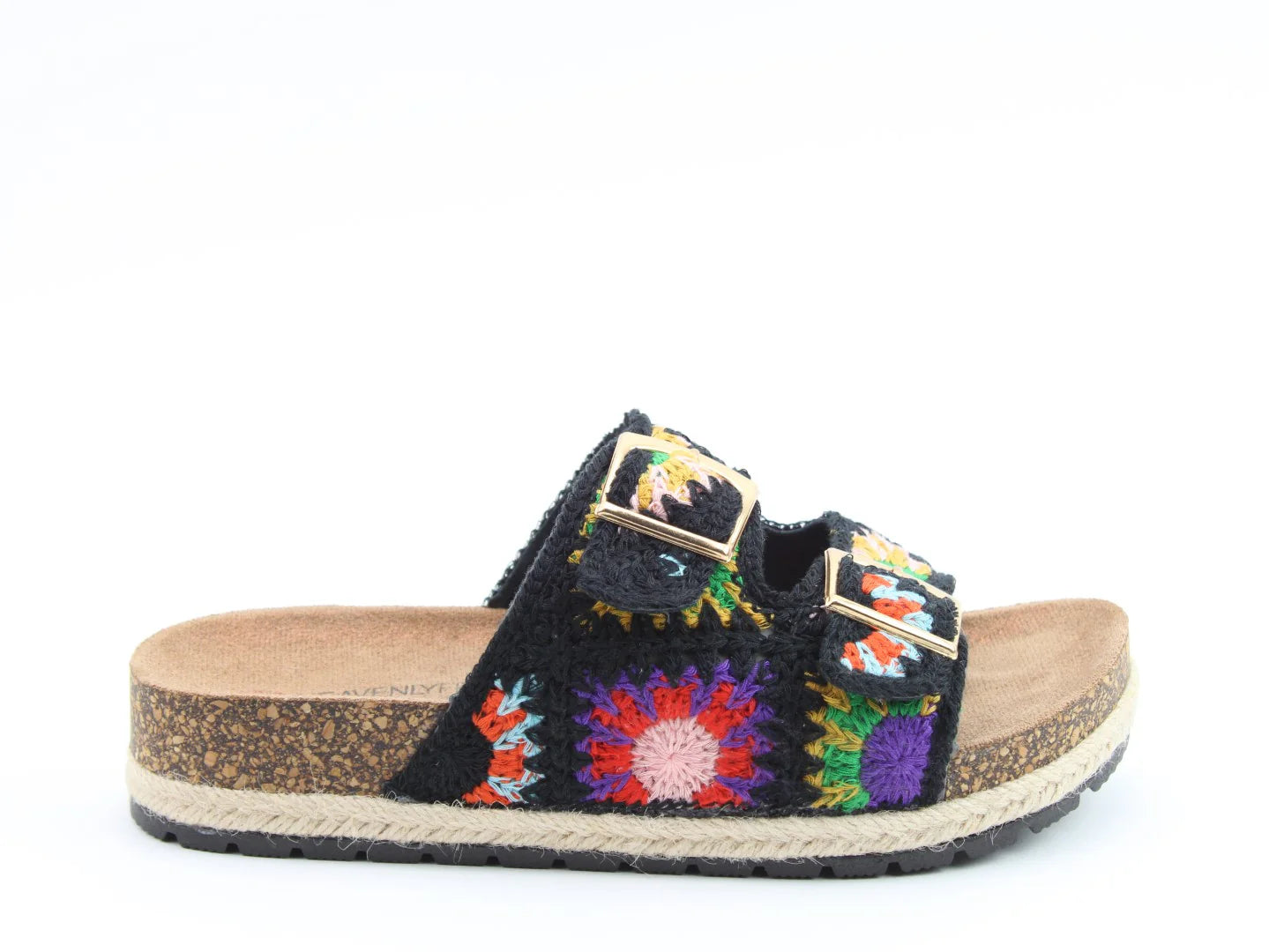 A black slip-on sandal with a cork sole, open toe, two buckled straps, and a colourful stitched upper featuring crochet flower patterns. Includes a contoured footbed for added comfort.