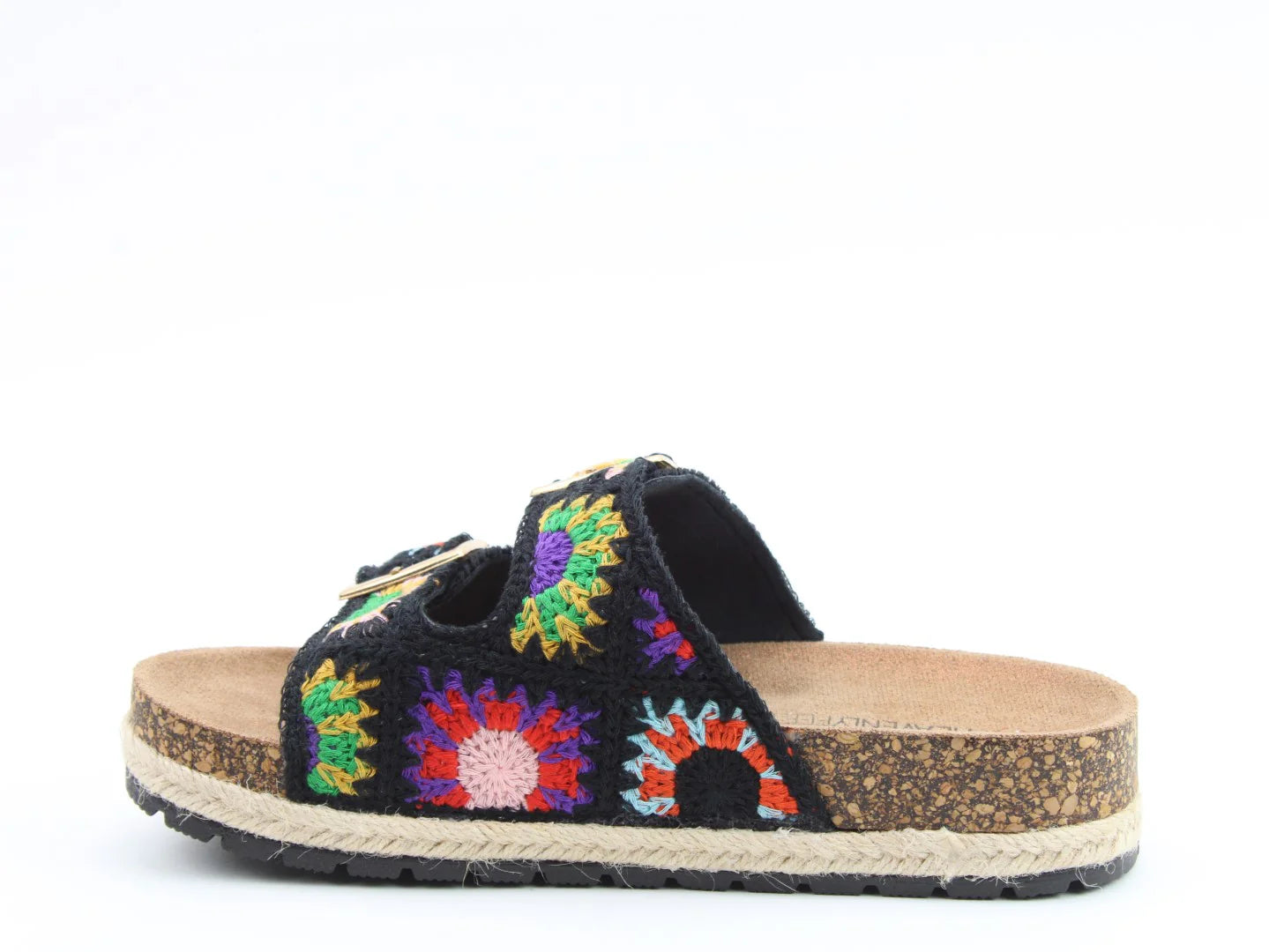 A black, vegan-friendly sandal featuring colourful stitched crochet patterns on the upper, two buckle straps, a contoured footbed, cork sole, and black rubber tread, displayed against a white background.