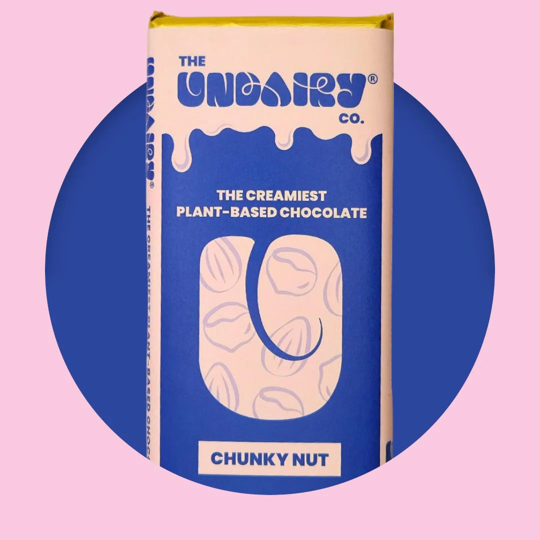A blue and yellow chocolate bar wrapper labelled The UnDairy Co. The creamiest no-dairy chocolate, Chunky Nut, with a vegan twist against a pink and blue background.