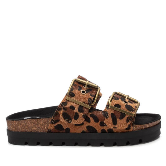 A slide sandal featuring a cork footbed, black sole, and two leopard-print vegan leather straps—each with a gold buckle. PETA-certified womens leopard sandals offering both style and comfort.