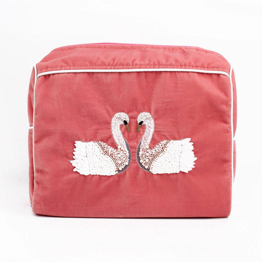 The Double Swan Large Pouch is a pink velvet pouch adorned with embroidered swans facing one another, detailed with white and metallic accents.