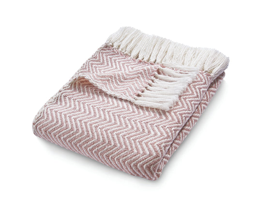 An eco-friendly pink and white herringbone throw, crafted from recycled plastic bottles, features fringed edges for a stylish touch.